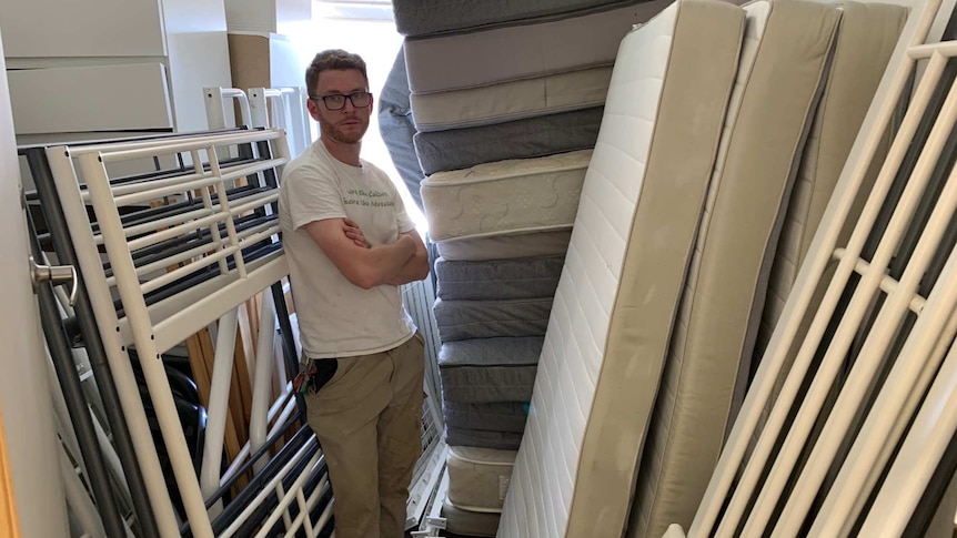A man surrounded by stacked mattresses