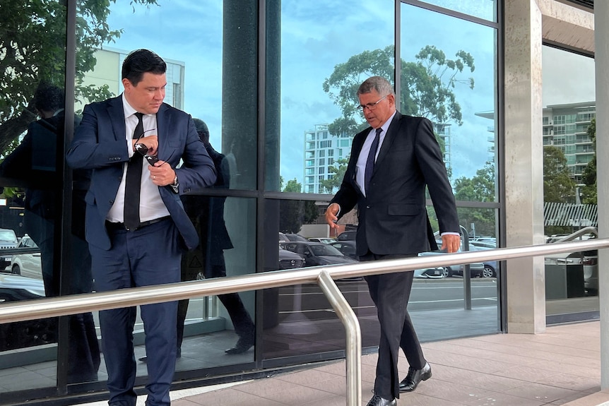 Two men in suits exit a court building.