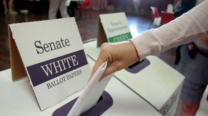 A hand places their Senate ballot paper in a ballot box