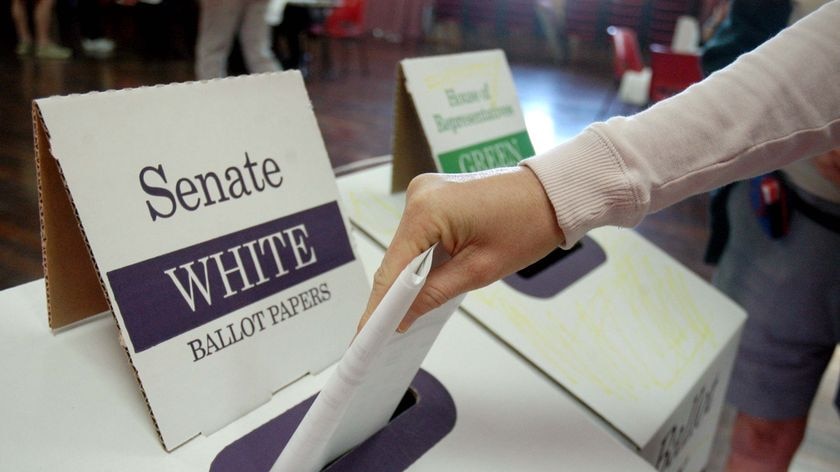 A voter places their Senate ballot paper in a box.