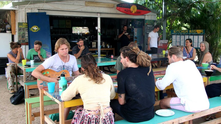 A group of people sitting at tables at a protest camp