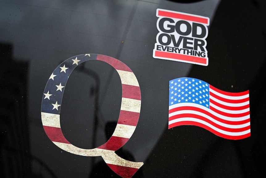 QAnon sticker, US flag sticker, and 'God over everything' sticker on black car