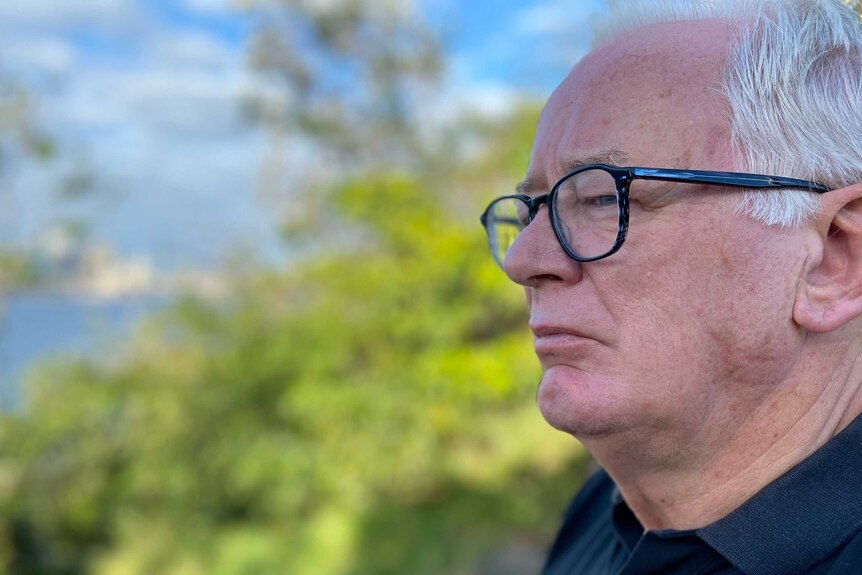 A man wears glasses and a black shirt.