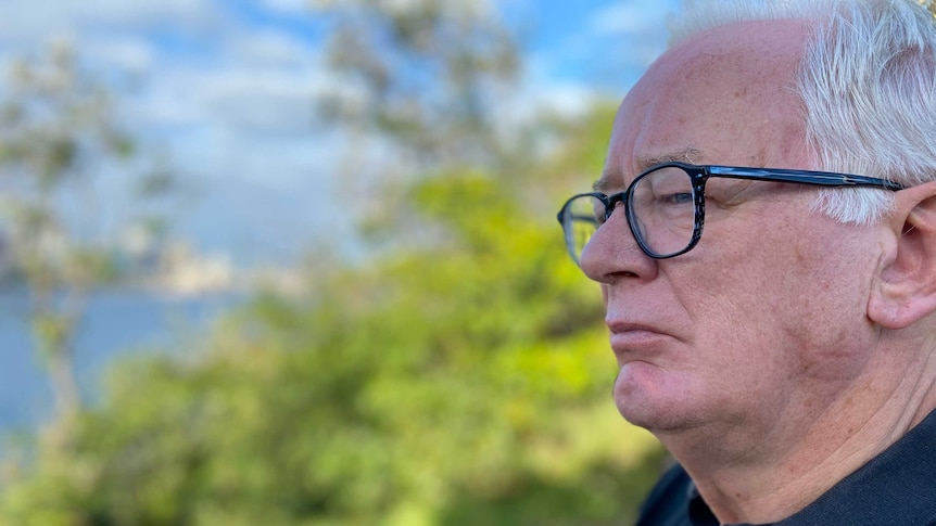 A man wears glasses and a black shirt.