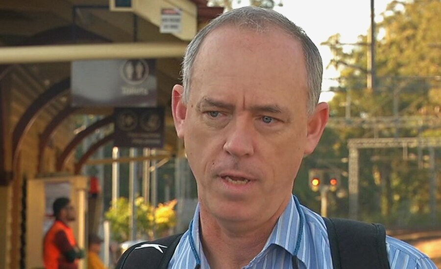 A man standing on the platform of a regional railway station