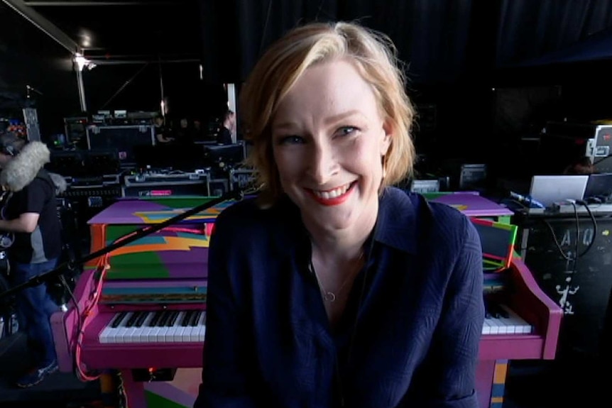 A smiling Leigh Sales sits at Paul McCartney's Magic piano