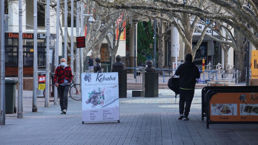 Two people wearing face masks walk in the Canberra city centre.