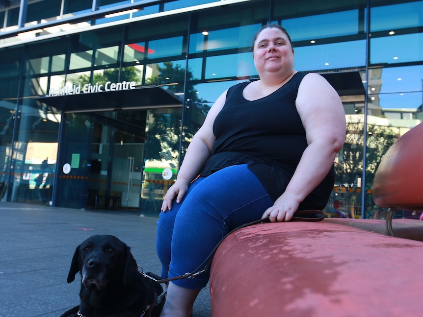 A young person sitting on a red bench with their guide dog