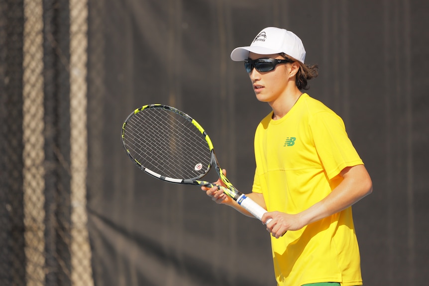 Simon Ma playing tennis in a yellow shirt