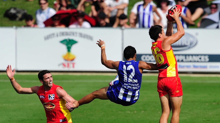 Gold Coast's Greg Broughton takes a mark ahead of North Melbourne's Lindsay Thomas in Townsville.