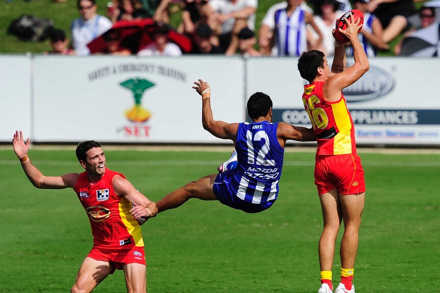 Gold Coast's Greg Broughton takes a mark ahead of North Melbourne's Lindsay Thomas in Townsville.
