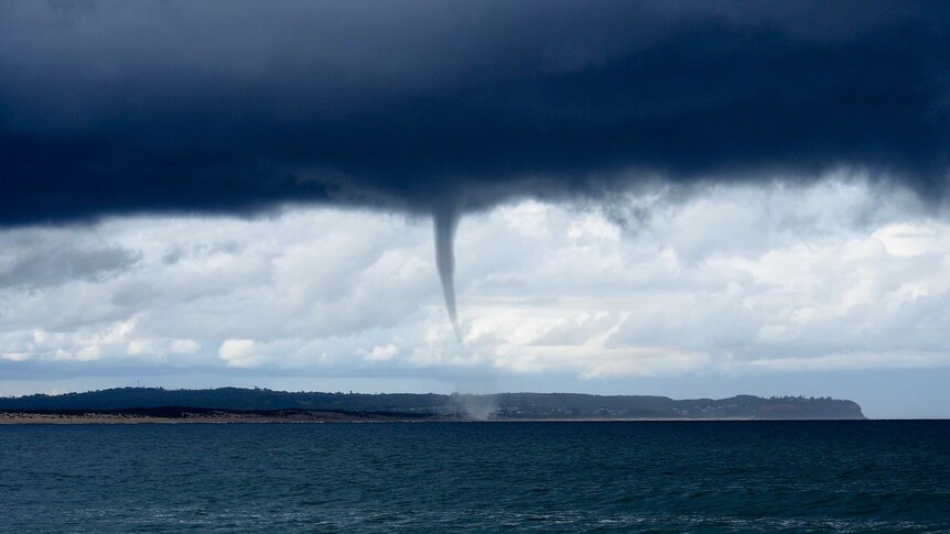 A waterspout forms over the ocean.