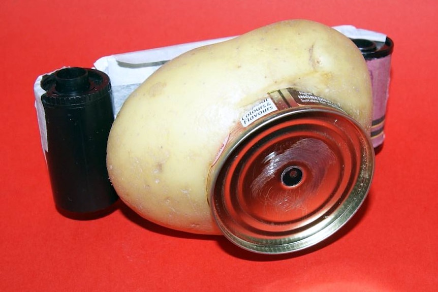 A potato, tin, film canister camera on a red background.