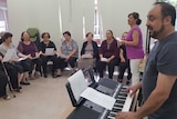 Man plays keyboard as women sing