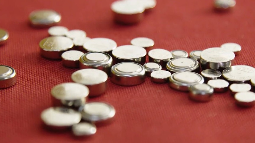 Button batteries sitting on a red carpet.