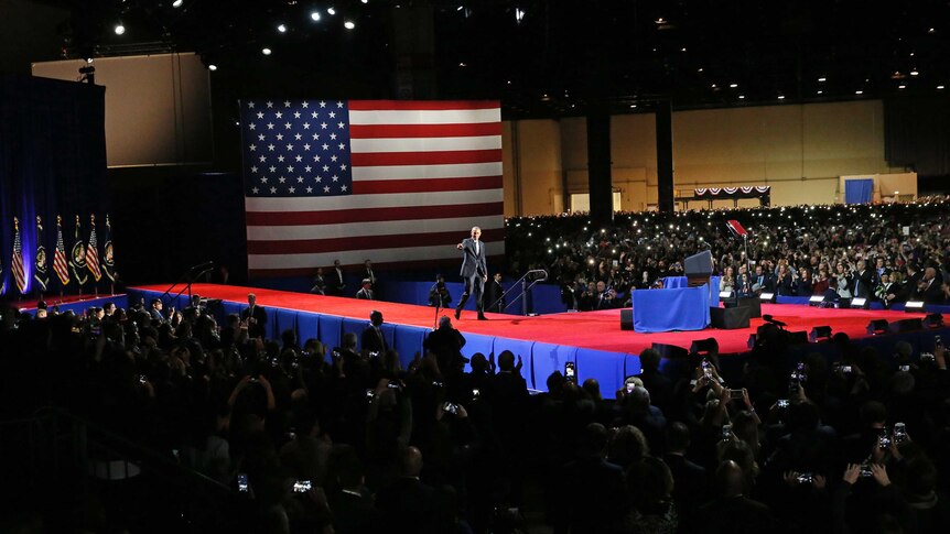 Barack Obama stands on stage surrounded by crowd at his farewell address in Chicago.