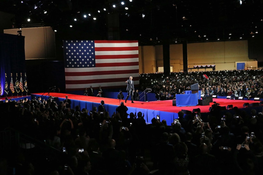 Barack Obama stands on stage surrounded by crowd at his farewell address in Chicago.