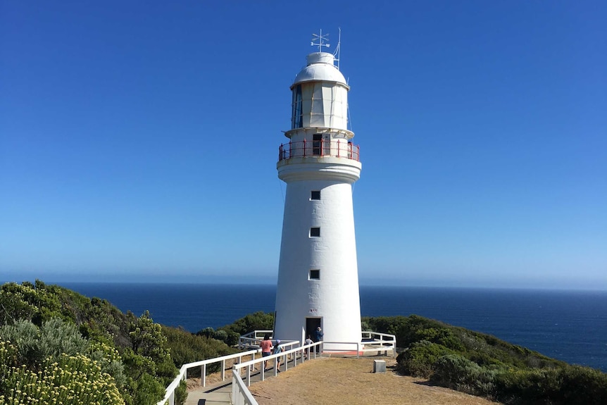 A lighthouse overlooks the ocean on a sunny day