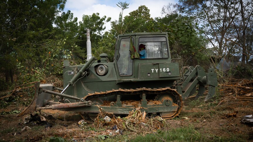 A bulldozer can seen seen clearing wood and debris 