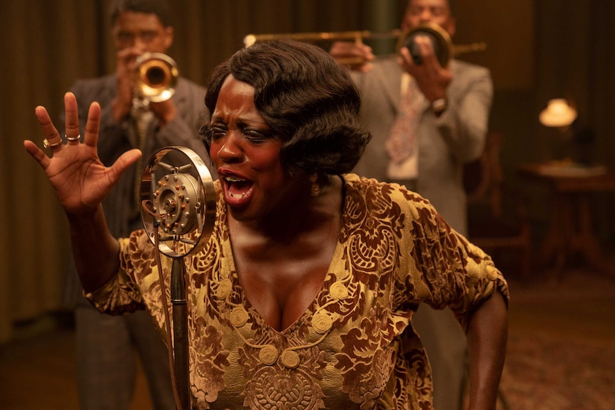 A scene from Ma Rainey's Black Bottom with Viola Davis singing passionately into a 1920s microphone