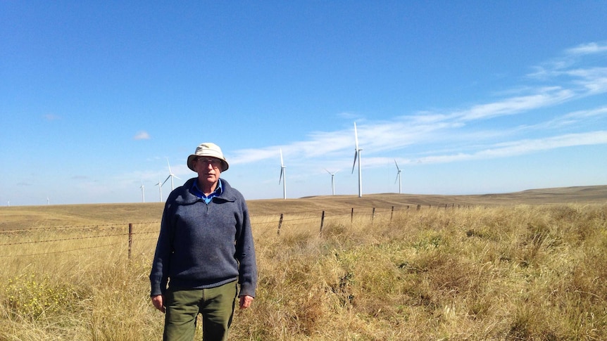 Howard Charles stands in front of seven wind turbines on his property in south-east NSW.