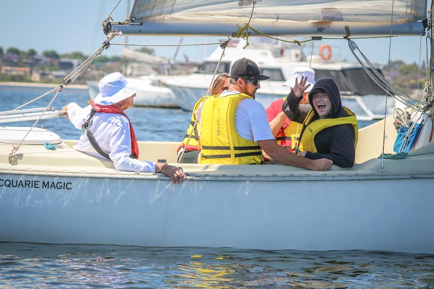 A man waves from a boat on the Swan River