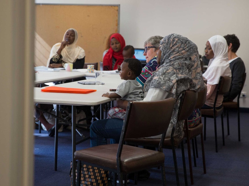 A group of women sit in a class room like setting.