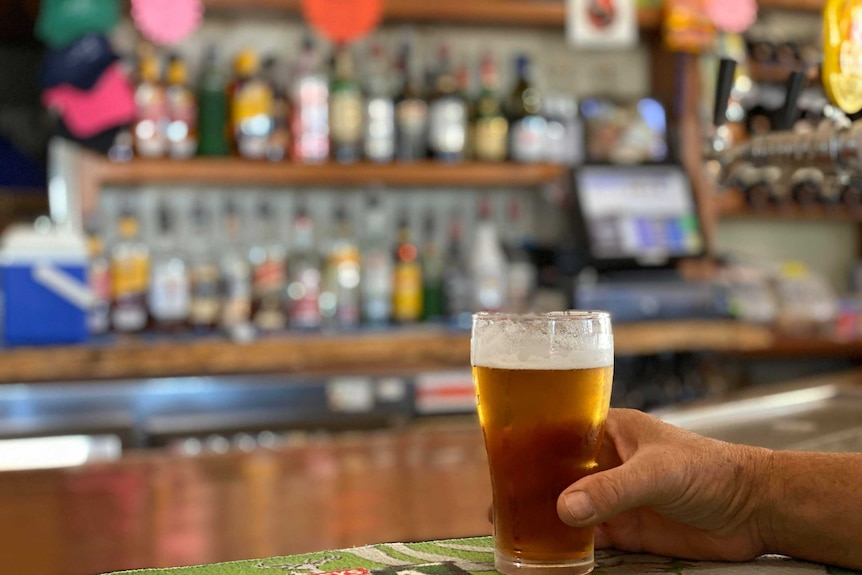 A hand wrapped around a cold beer in a pub