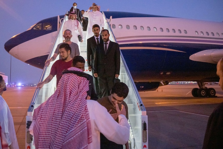 People walk down stairs from plane.