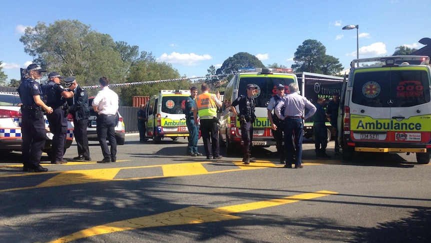 Police and paramedics discuss the stabbing at Beenleigh.