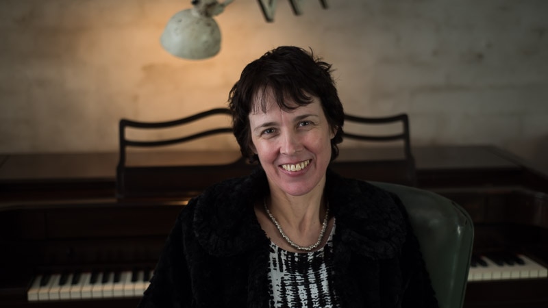 Andrea Keller sitting in front of a piano.