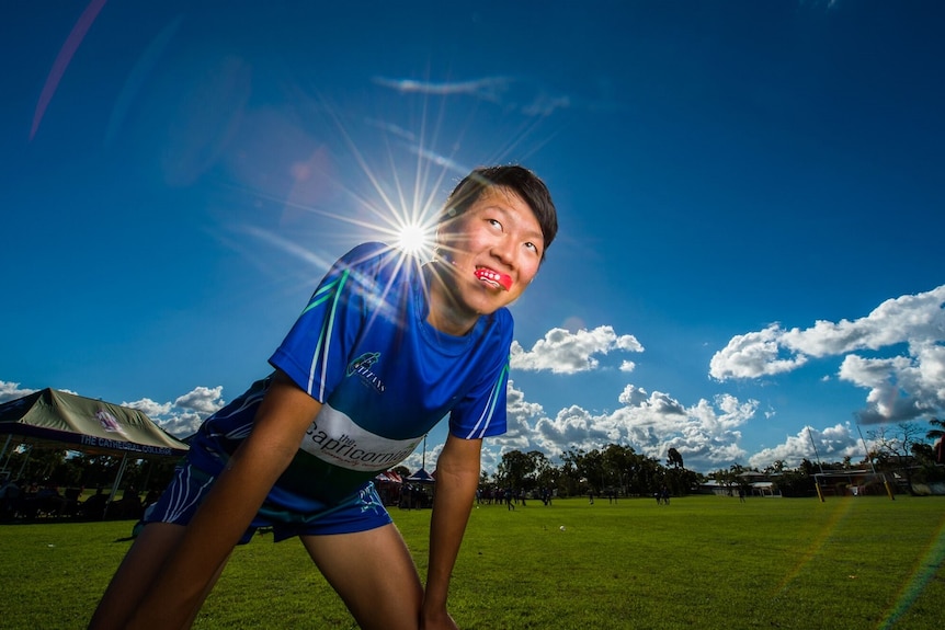 Heetae Lim bending over, hands on knees, mouthguard in, sun shining behind.