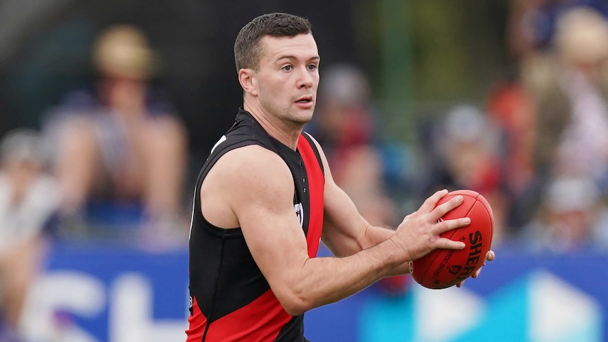 Conor McKenna holds a red AFL ball in both hands