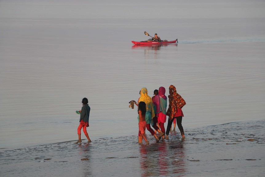 A group of Bangladeshi women watch global adventurer Sandy Robson paddle her kayak offshore.