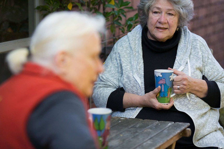 Kristin looks at Hilary over a cup of coffee in the garden.