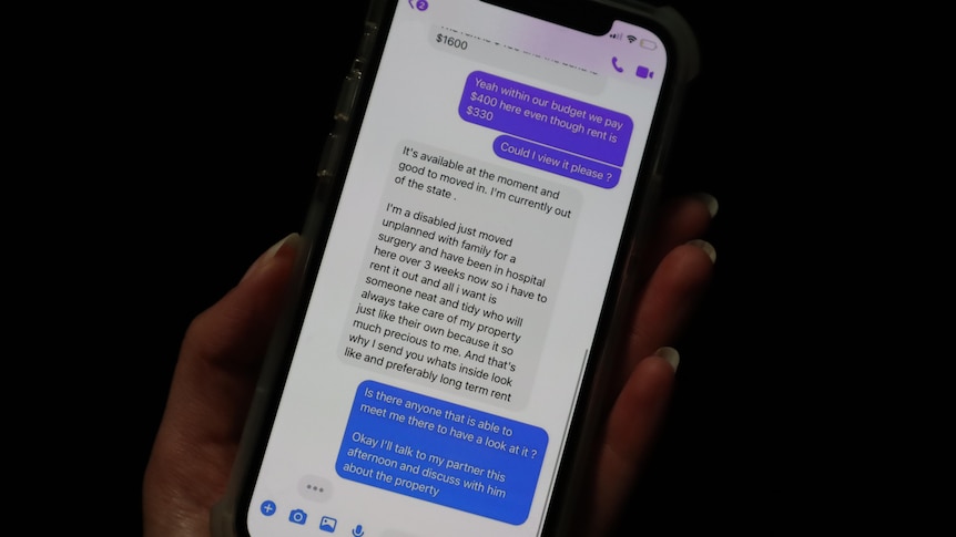 A hand holding a phone with messages from someone trying to scam them into paying for a rental that doesn't exist.