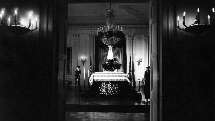 The flag-draped casket of JFK lies in state in the East Room of the White House.