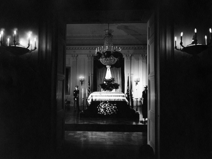 The flag-draped casket of JFK lies in state in the East Room of the White House.
