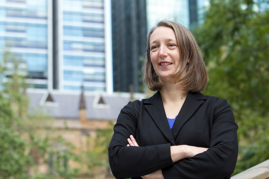 A woman wearing a black blazer crosses her arms.