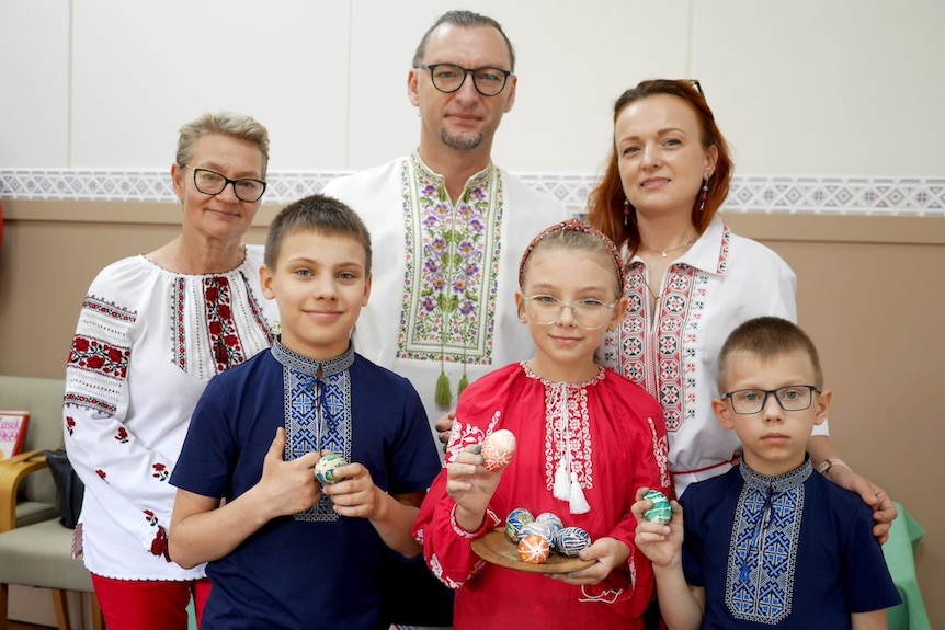 A family of five wearing traditional Ukrainian dress hold pysanka eggs