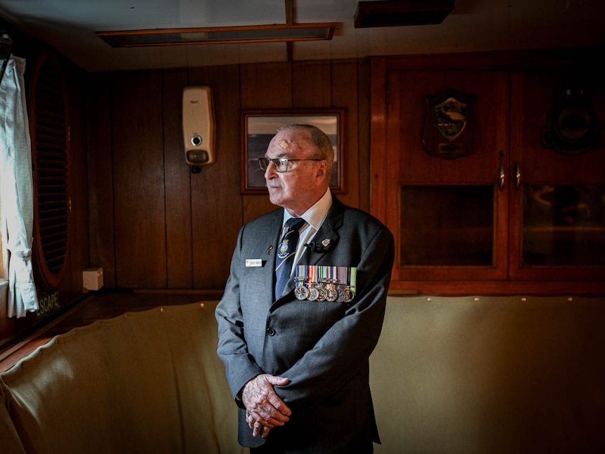 An older man wearing his decorated military uniform aboard a destroyer ship