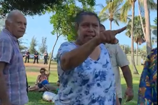 Woman pointing out of shot in a park.