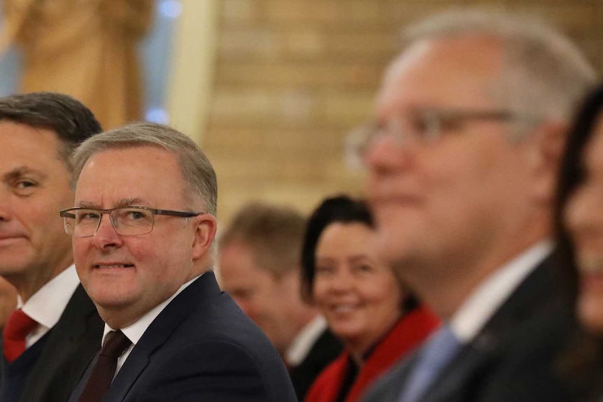 Richard Marles and Anthony Albanese sit on one side of a church aisle. Prime Minister Scott Morrison sits on the other side.