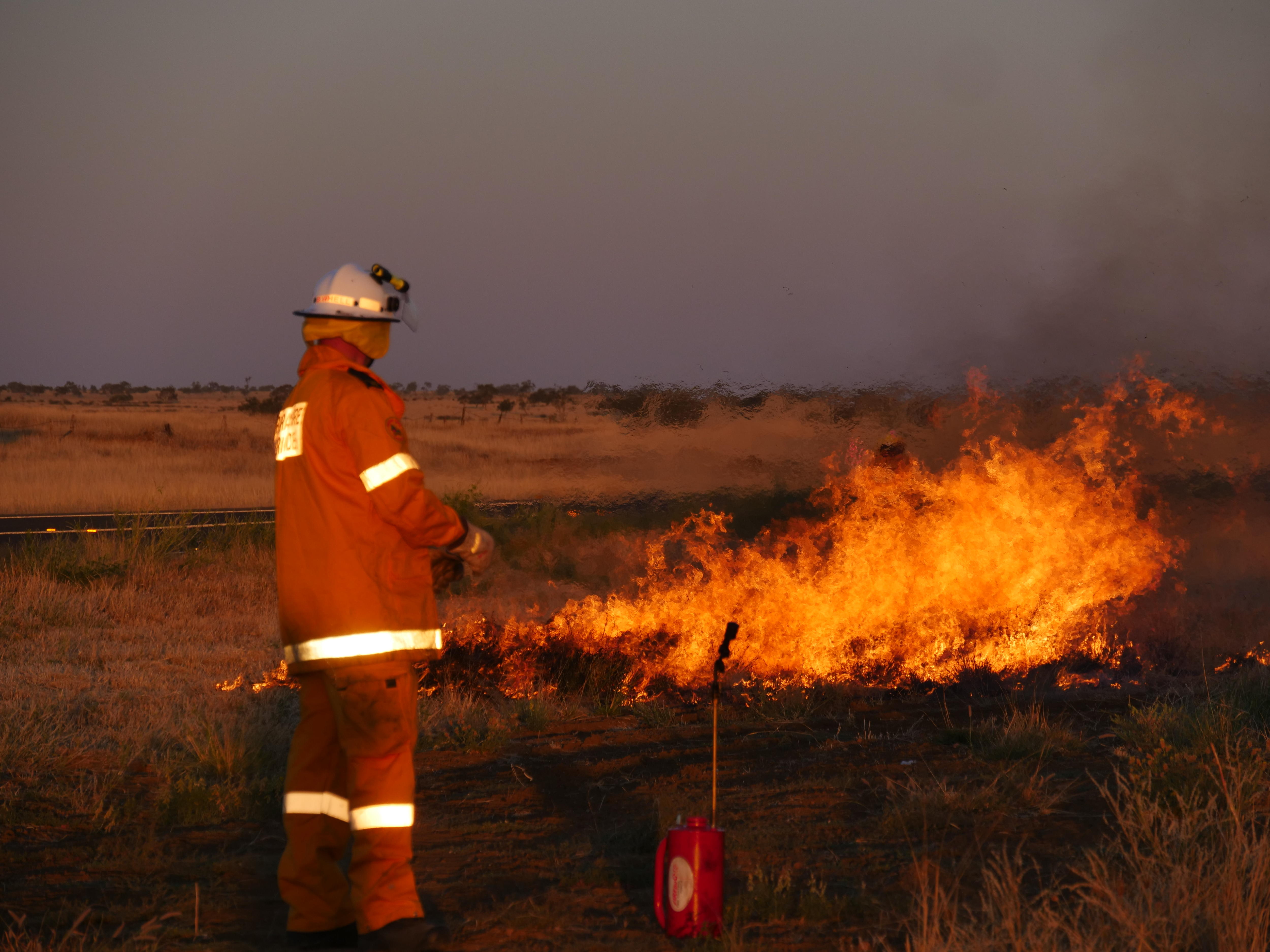 Un bombero se encuentra en tierra y realiza una quema en la espalda.