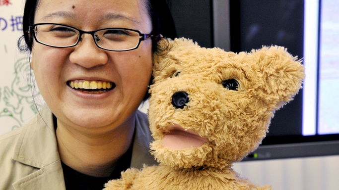 A Fujitsu employee demonstrates a teddy bear shaped "social" robot