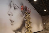 Brisbane artist Guido van Helten spray paints a portrait on the inside wall of the Lion Flour warehouse.