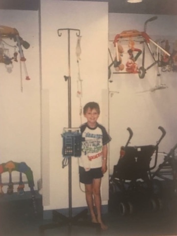 A young boy standing next to a drip stand