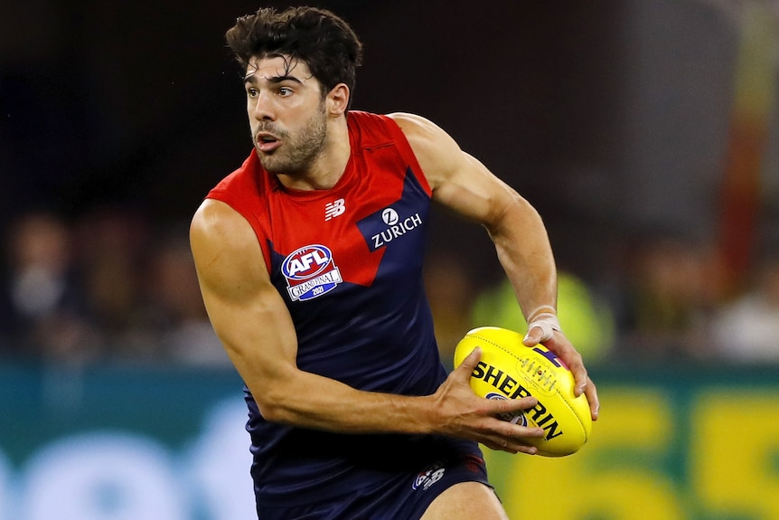 A Melbourne Demons AFL player holds the ball in two hands in the grand final