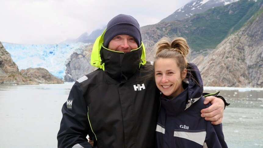 Couple standing together in front of a glacier.