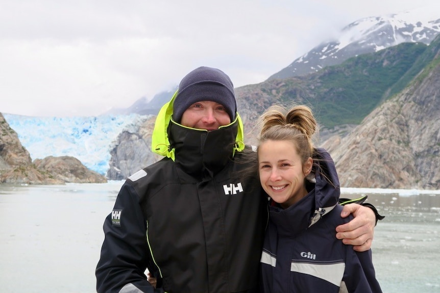 Couple standing together in front of a glacier.